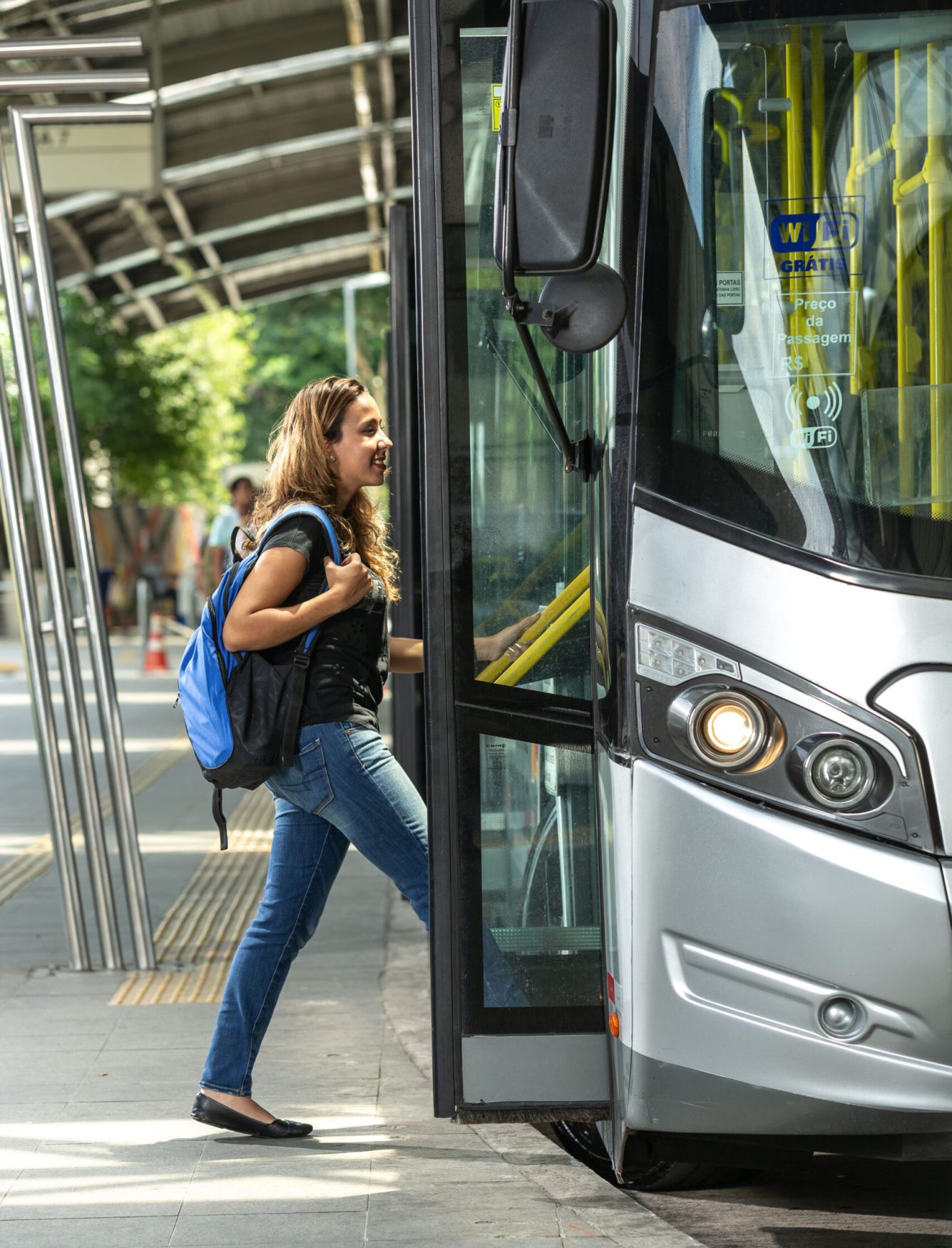 Student or girl getting on a municipal bus, with backpack on their back, in a beautiful and modern terminal